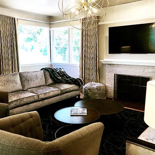 A living room with a couch, chairs, tables, and a fireplace.