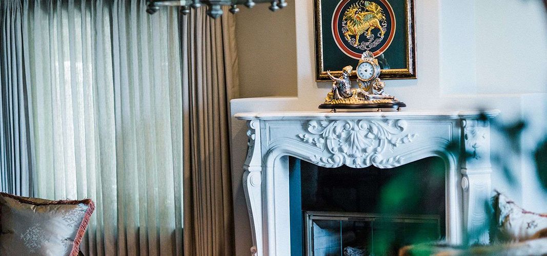 A living room with a fireplace and a clock on the mantle.
