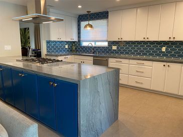 A kitchen with blue cabinets, white cabinets, and a large island.