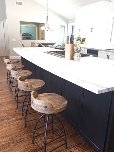 A kitchen with a large island and wooden bar stools.