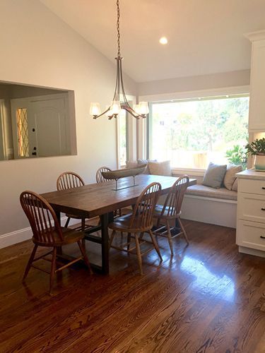 A dining room with a table and chairs and a window seat.