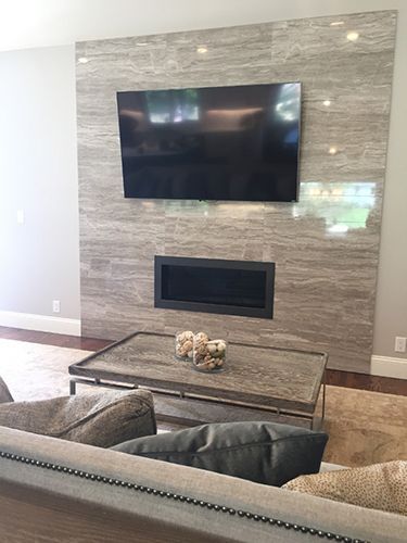 A living room with a fireplace and a flat screen tv on the wall.