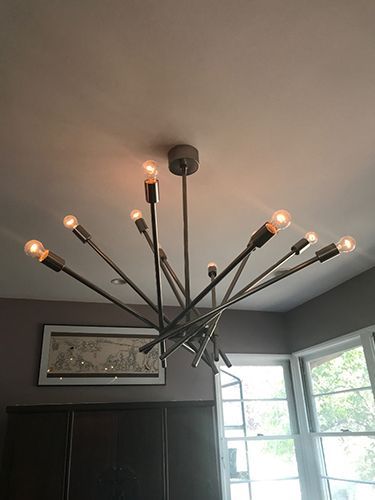 A chandelier is hanging from the ceiling in a room next to a window.
