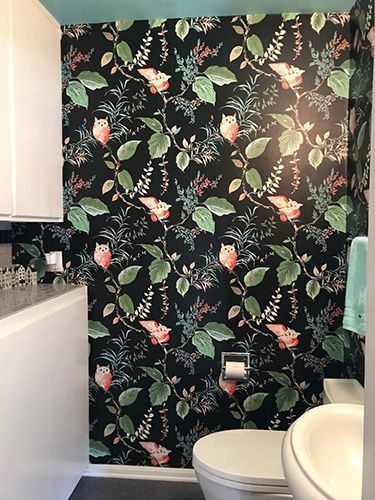 A bathroom with a toilet, sink, and floral wallpaper.