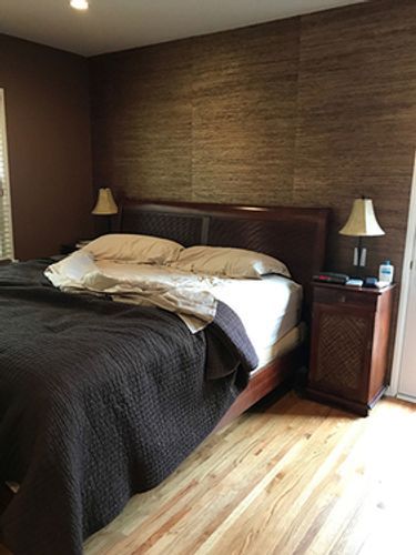 A bedroom with a bed, nightstand, and lamps.