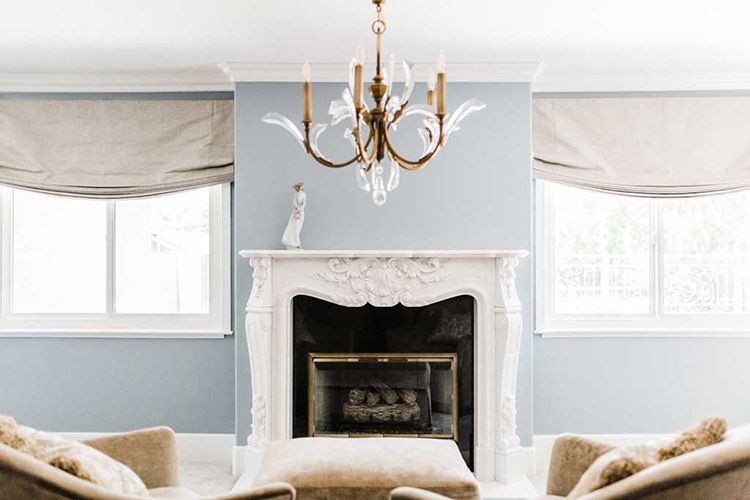 A living room with a fireplace, chairs, and a chandelier.