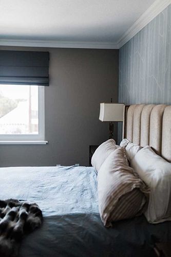 A bedroom with a bed, lamp, and window.