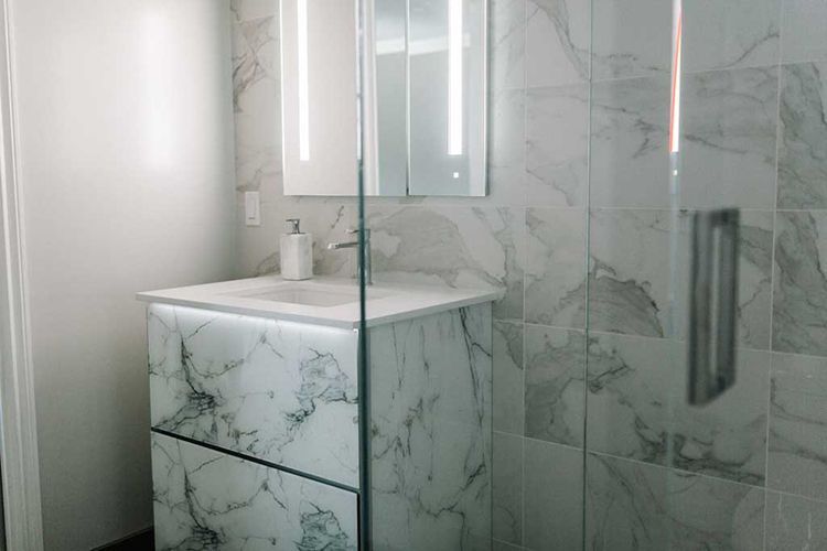 A bathroom with a sink, mirror, and walk in shower.