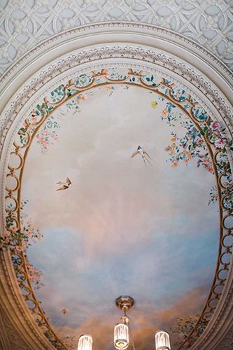 A ceiling with a painting of birds and flowers on it.