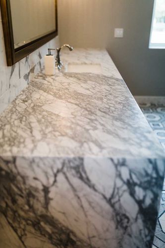A bathroom sink with a marble counter top and a mirror.