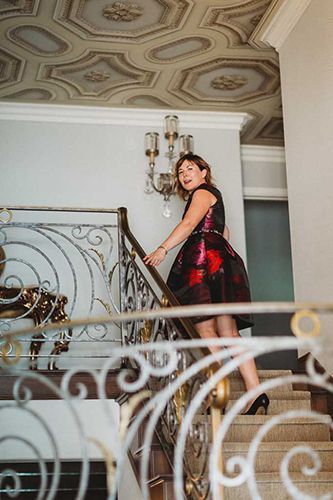 A woman in a red dress is standing on a set of stairs.