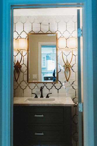 A bathroom with a sink , mirror and lamps.