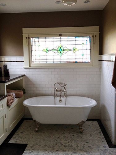 A bathroom with a bathtub and a stained glass window.