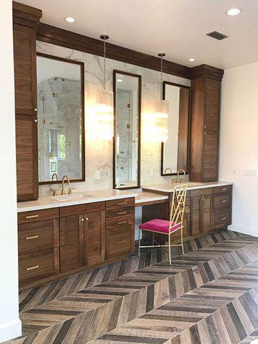 A bathroom with two sinks, two mirrors and a chair.