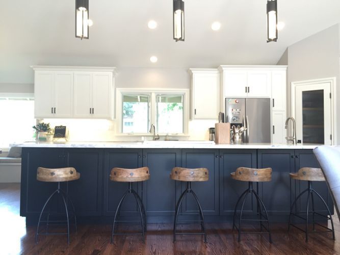 A kitchen with blue cabinets and white cabinets and stools.