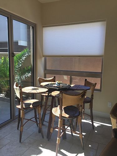 A dining room with a table and chairs in front of a window.