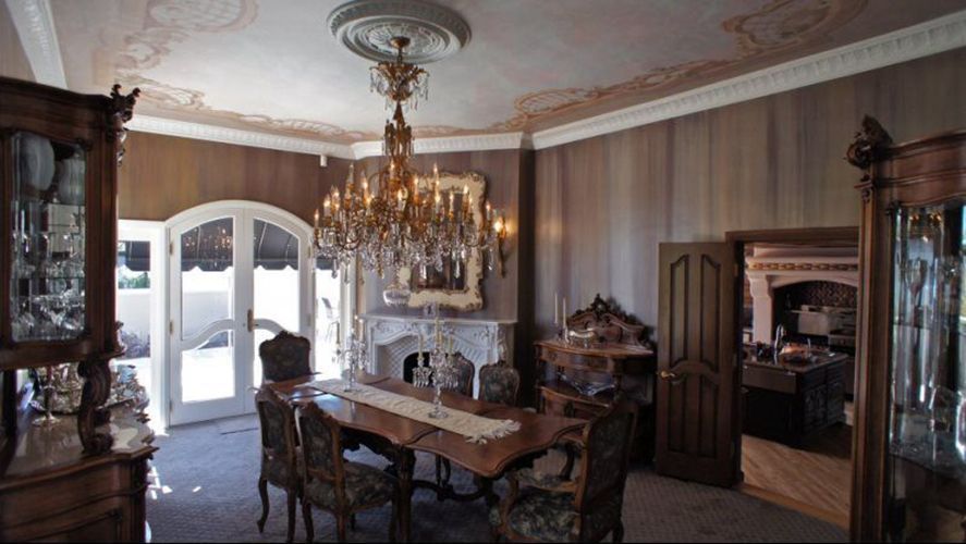 A dining room with a table and chairs and a chandelier hanging from the ceiling.