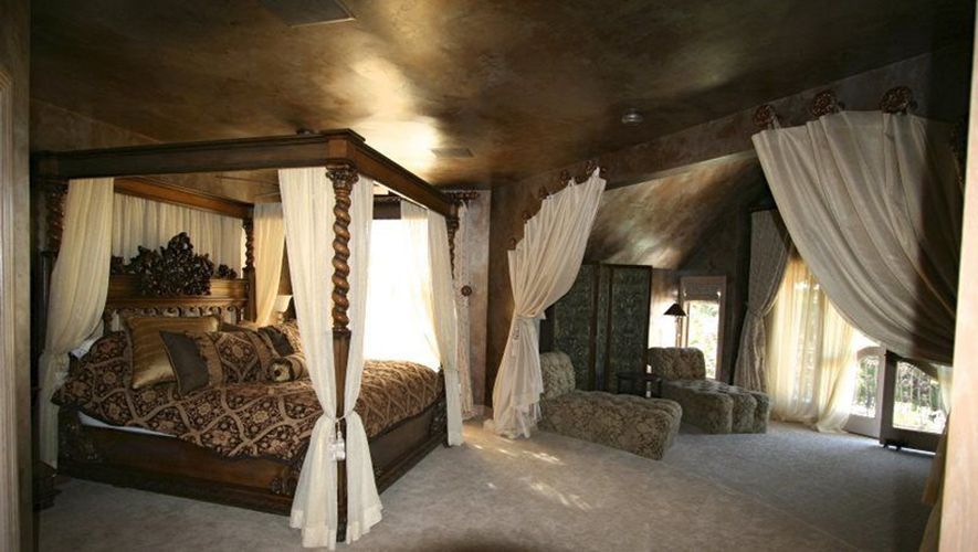 A bedroom with a canopy bed and a chair.