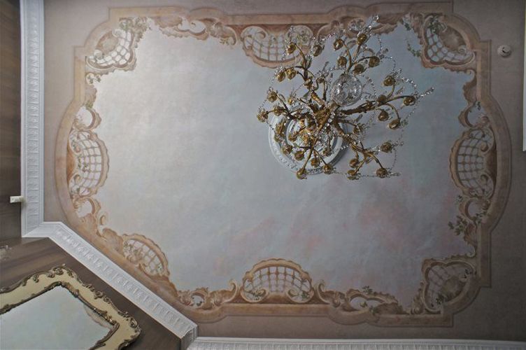 A chandelier is hanging from the ceiling of a room with a painting on it.