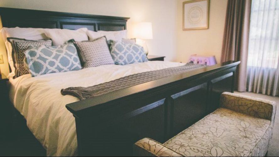 A bedroom with a large bed and a bench.