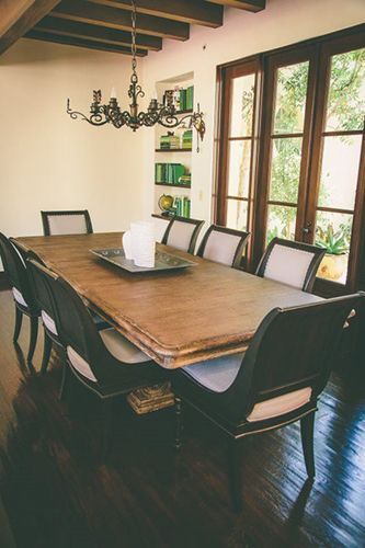 A dining room with a long wooden table and chairs.