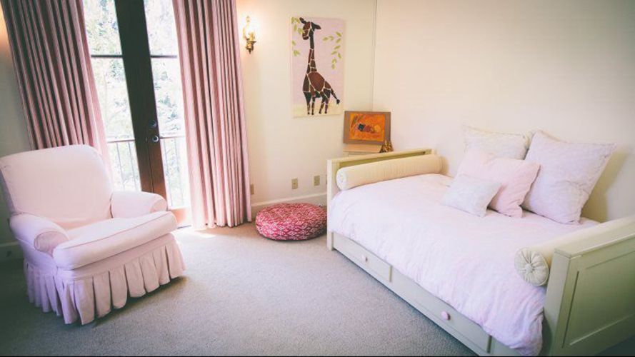A bedroom with a day bed, chair, and window.