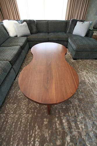 A wooden coffee table is sitting in a living room next to a sectional couch.