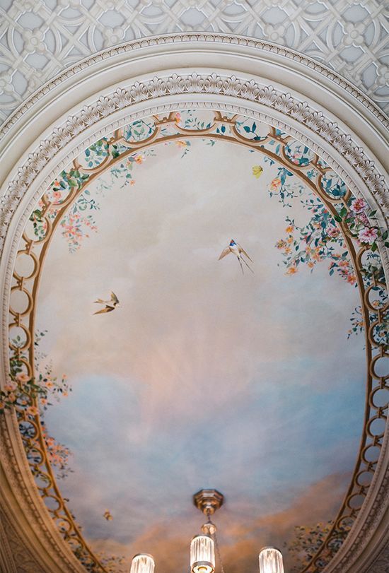 A ceiling with a painting of birds and flowers on it.