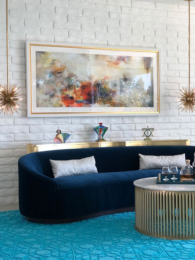 A living room with a blue couch, coffee table, and painting on the wall.