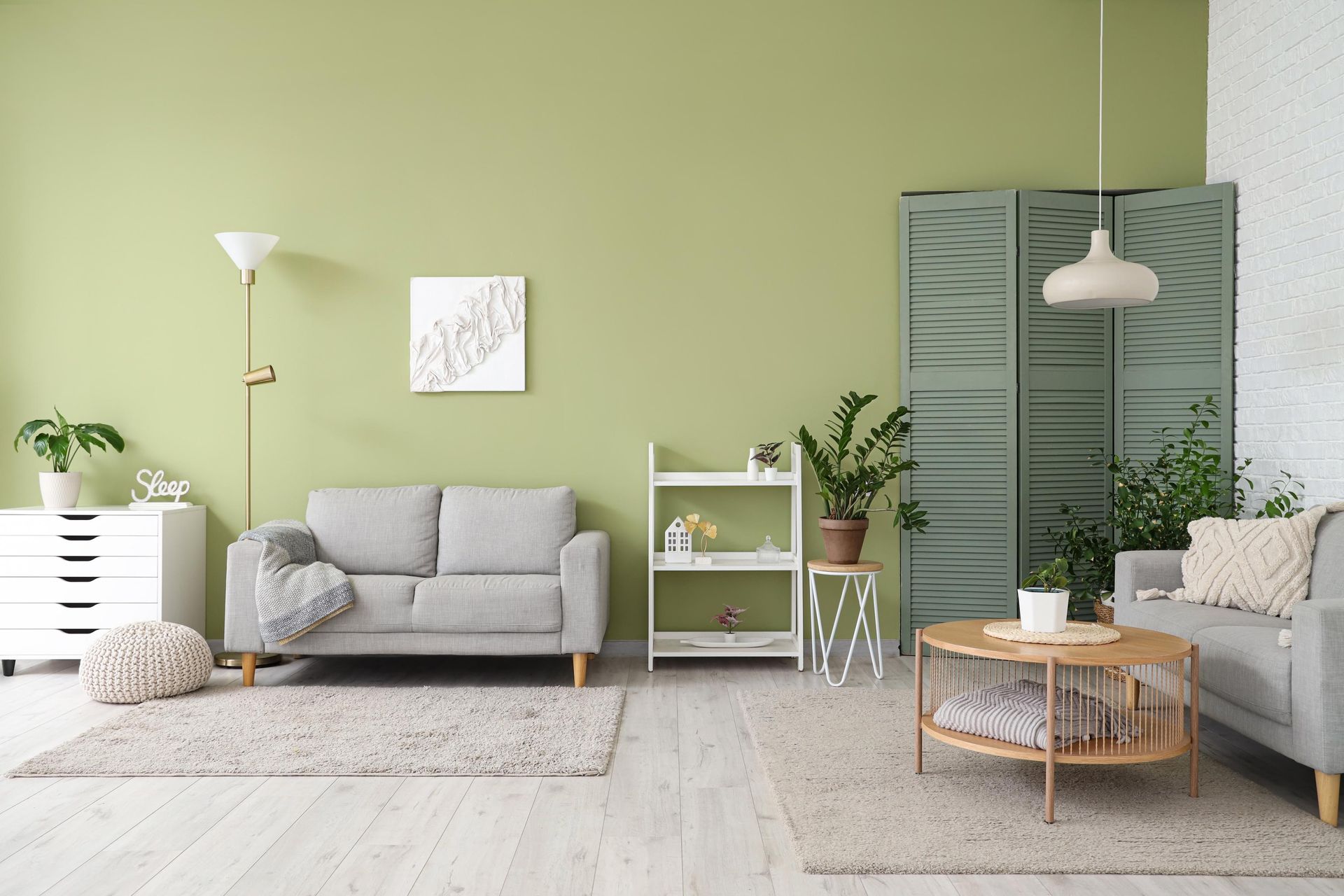A living room with green walls , a couch , a coffee table , and a dresser.