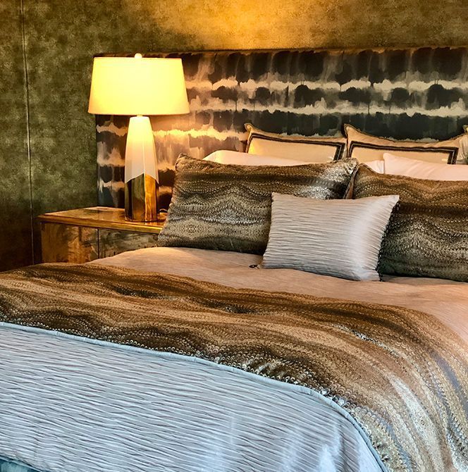 A bedroom with a large bed and a lamp.