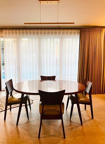 A dining room with a round table and chairs in front of a large window.
