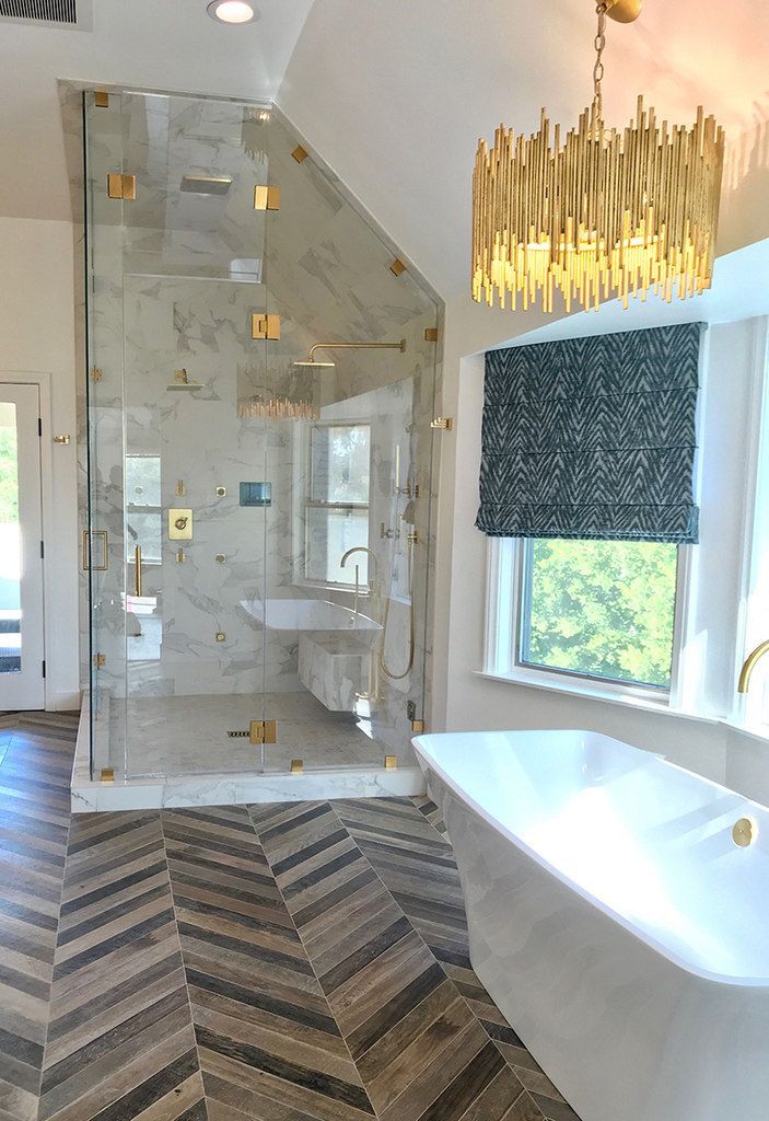 A bathroom with a walk-in shower, tub, sink, and window.