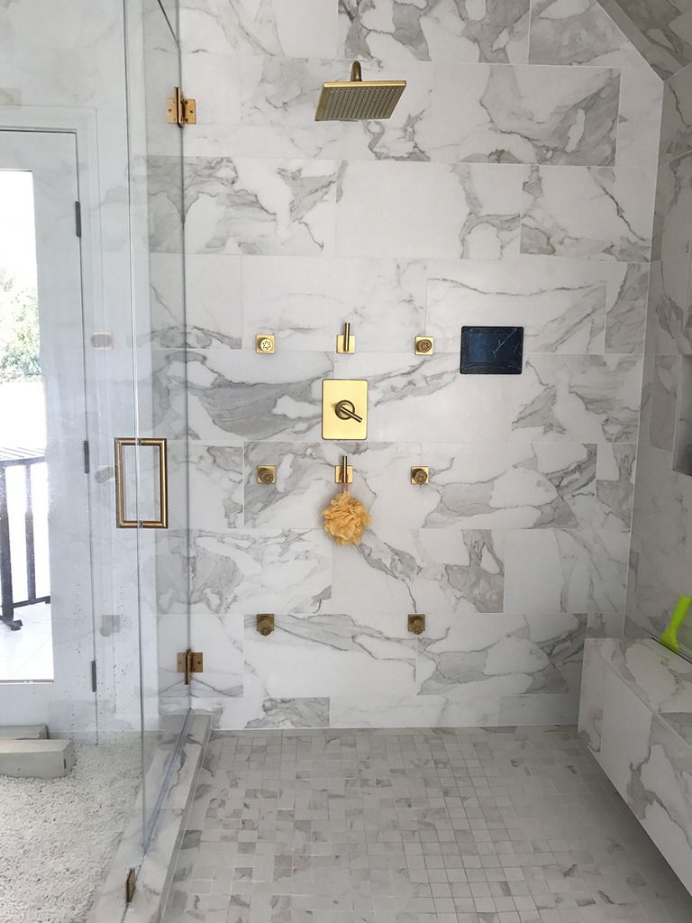 A bathroom with marble tiles and a walk in shower with a glass door.