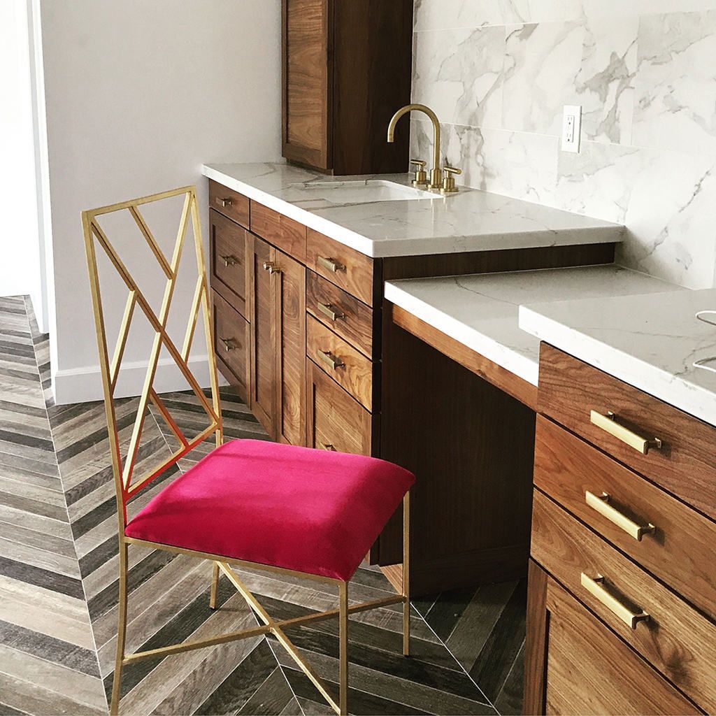 A chair with a pink seat is sitting next to a counter in a kitchen.