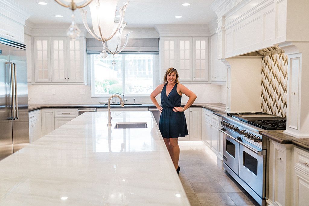 A woman in a blue dress is standing in a large kitchen.