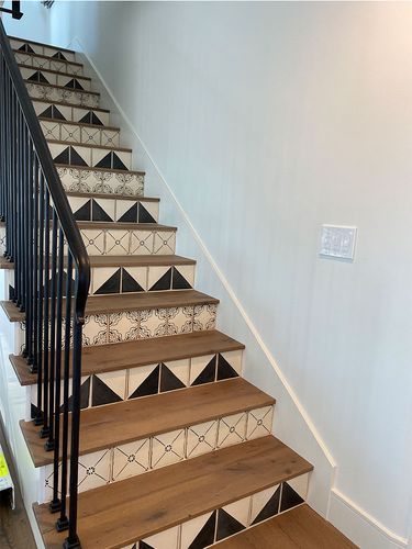 The stairs are made of wood and tile and have a black railing.