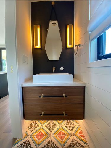 A bathroom with a sink , mirror and drawers.