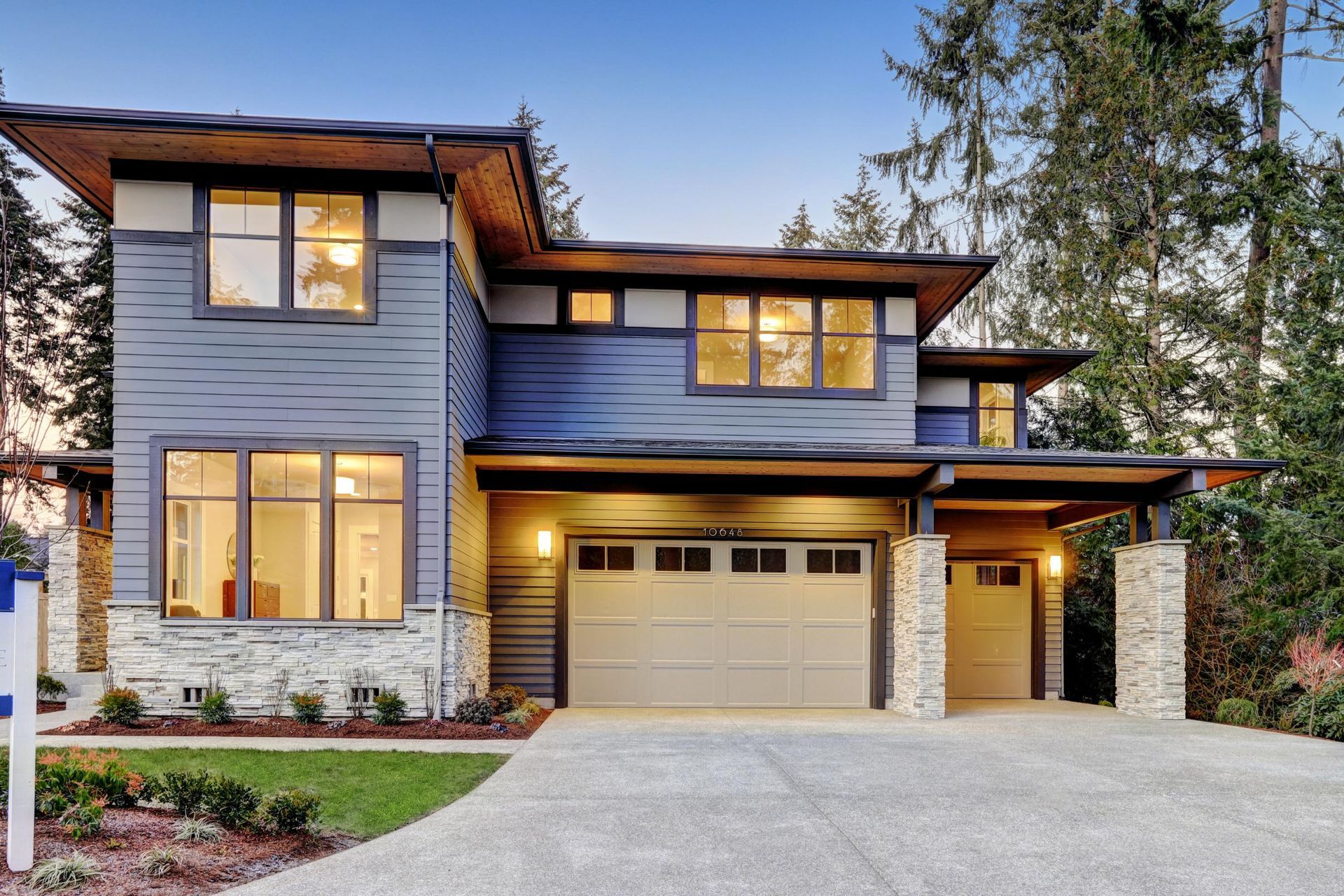 A large house with a garage and a for sale sign in front of it.