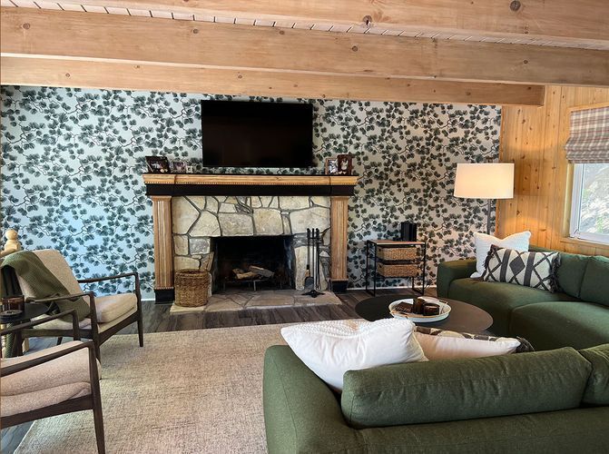 A living room with a green couch, chairs, and a fireplace.