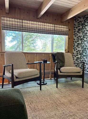 A living room with two chairs and a table in front of a window.