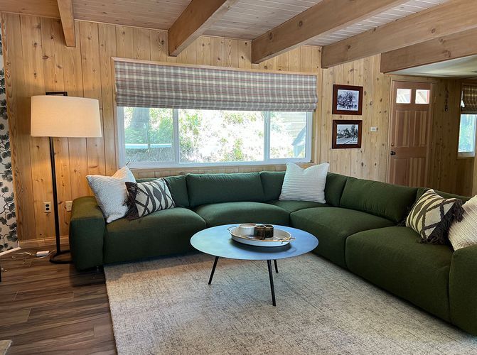 A living room with a green sectional couch and a white coffee table.