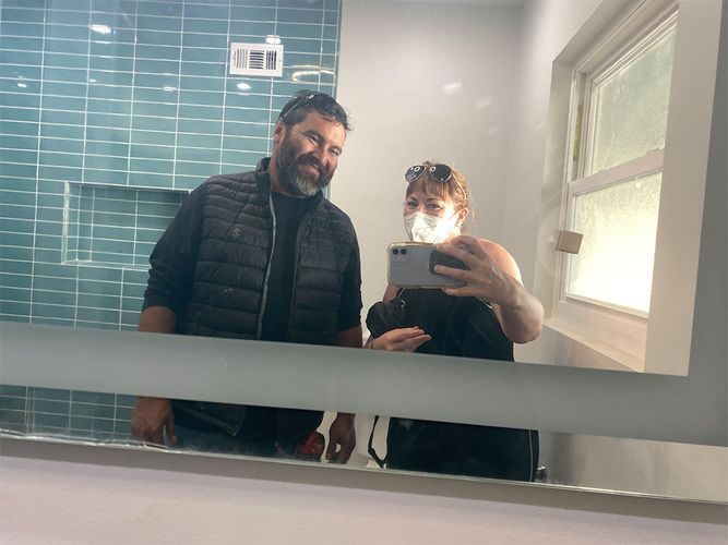 A man and a woman are taking a selfie in a bathroom mirror.