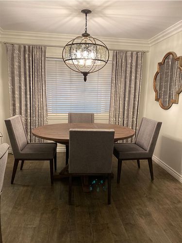 A dining room with a round table and chairs and a chandelier.