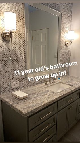 A bathroom with a sink , mirror and cabinets.