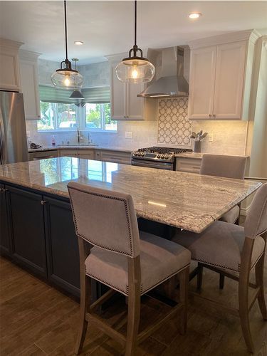 A kitchen with a large island and chairs and a stove.