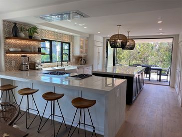 A kitchen with a large island , stools and a stove.