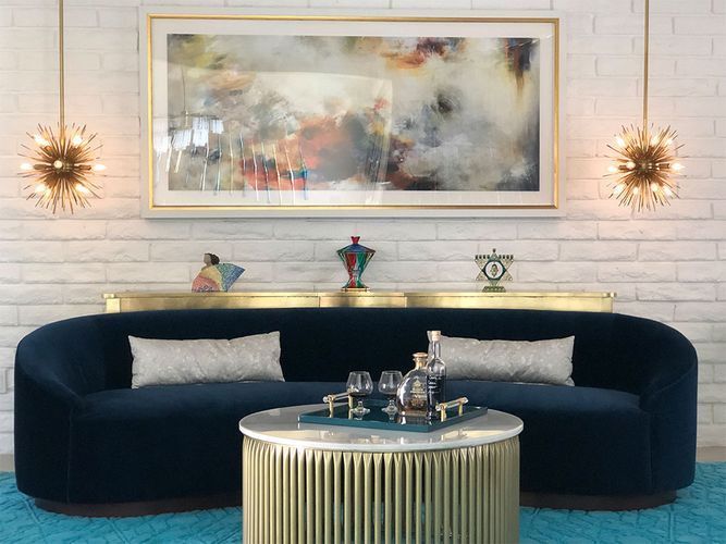 A living room with a blue couch and a gold coffee table.