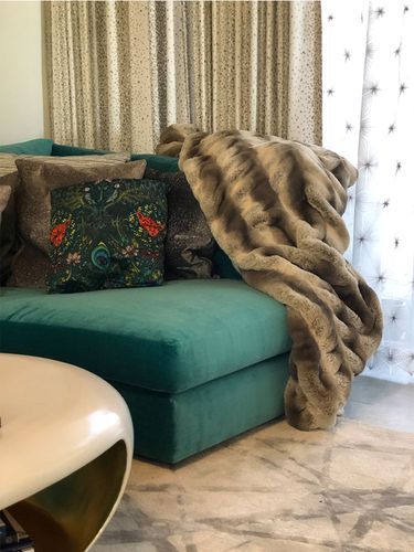 A living room with a green couch and a brown blanket.