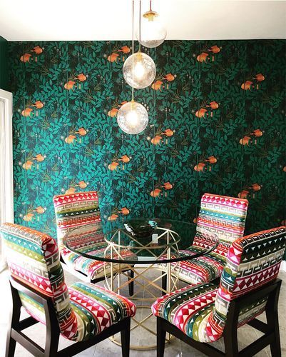 A dining room with colorful chairs and a glass table.